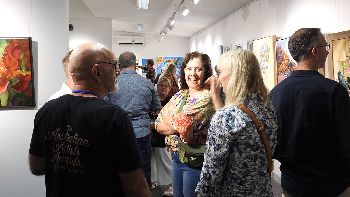 A crowd of people looking at paintings in the Australian Artists Awards exhibition