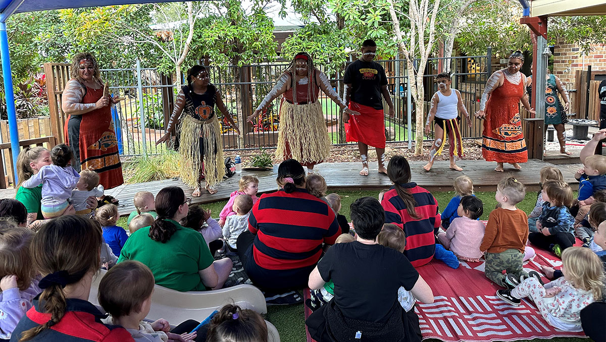 Indigenous dancers on stage in front of children