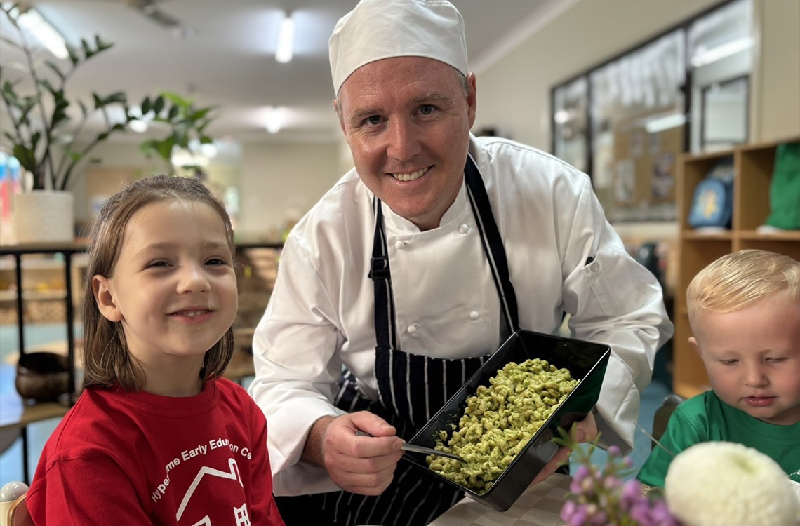 Chef serving pasta to kindy kids