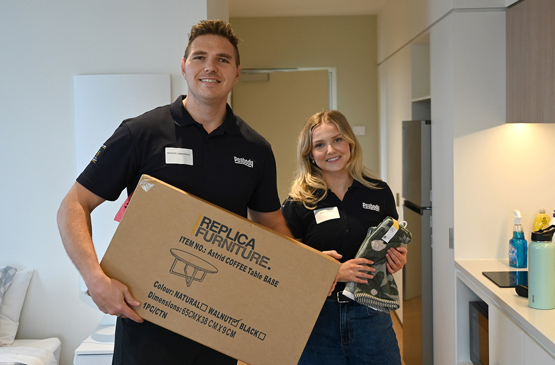 Man and woman holding a box in a brand new apartment