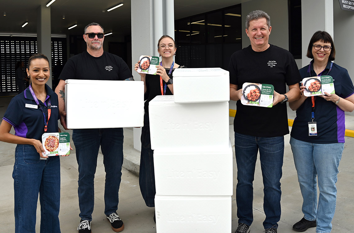 four people holding frozen meals with a stack of eskies