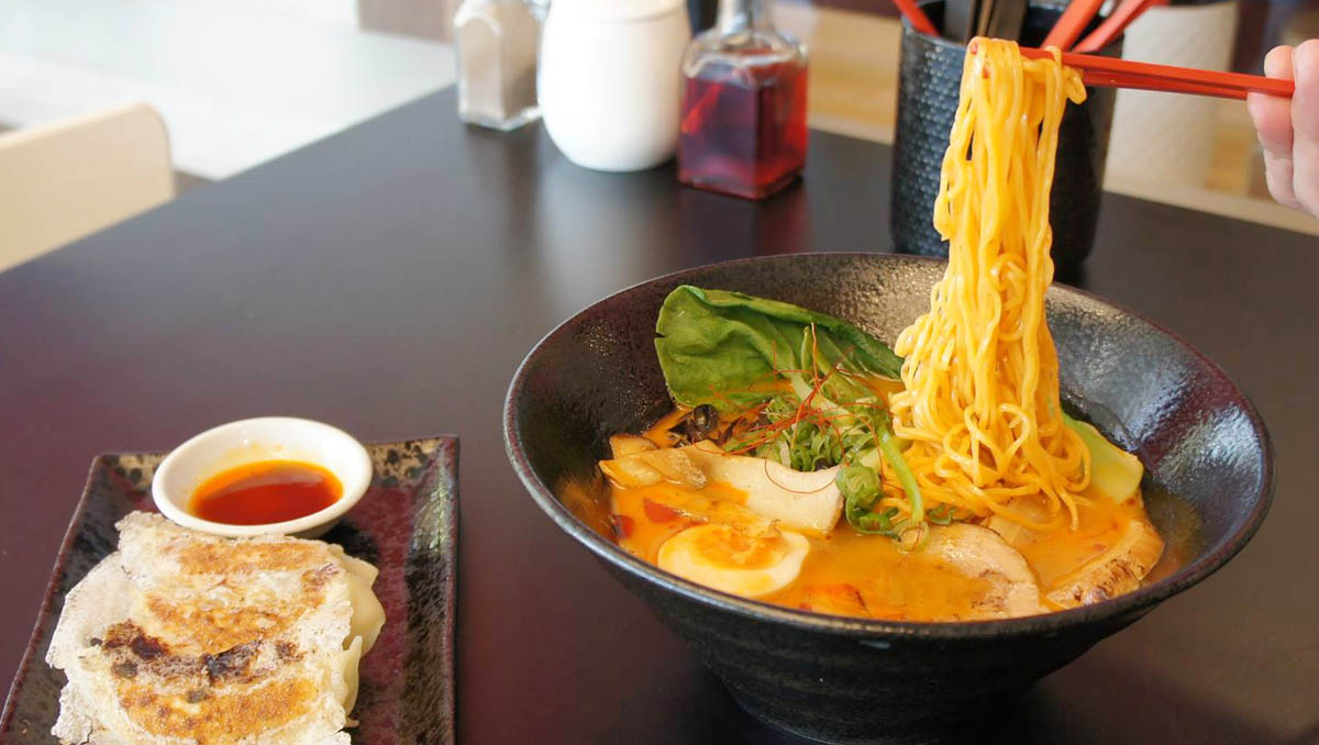 Ramen noodles and a side dish with sauce displayed on a table