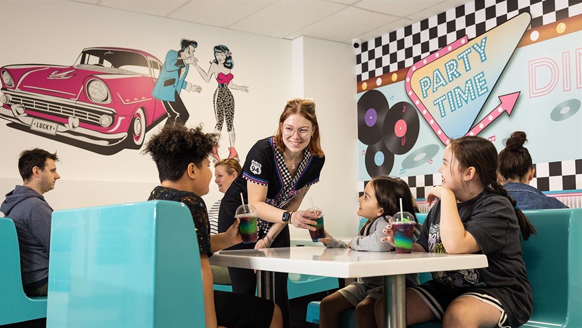 an diner inspired by Route 66 with car murals on the walls and diners sitting at a table