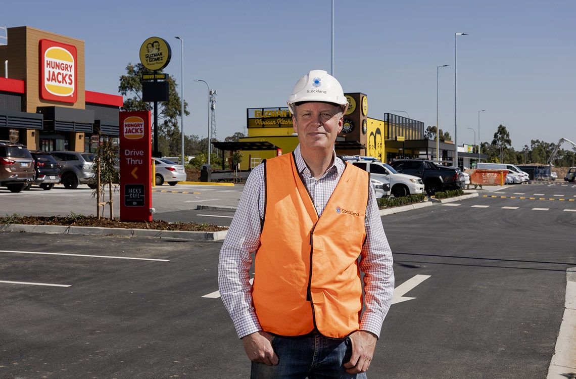 Stockland representative in a hard hat and high visibility vest standing in the carpark of the new retail precinct at Yarrabilba