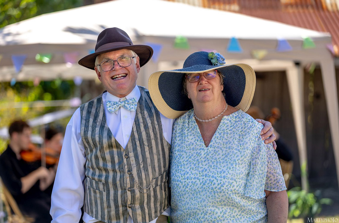 Man in waistcoat and woman in large hat at Mayes Cottage