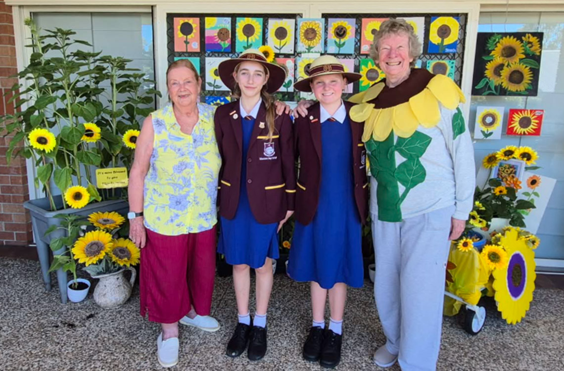 school children with reitrees next to sunflowers