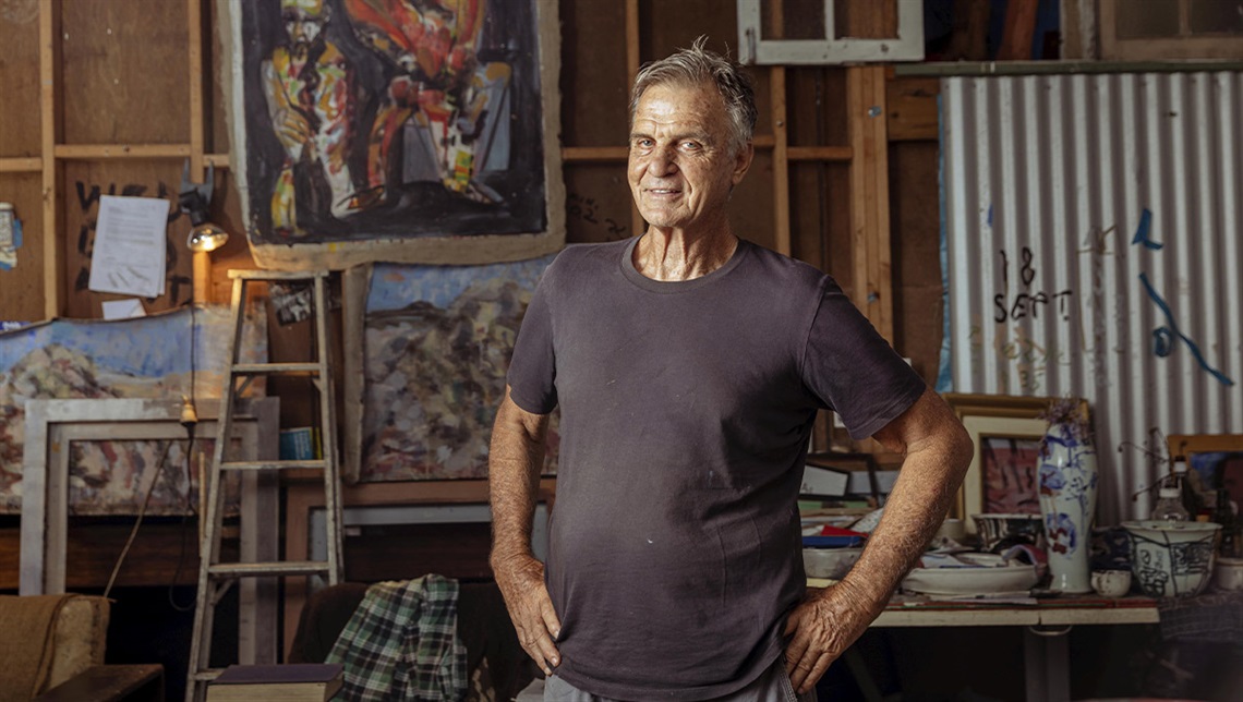 Joe Furlonger standing in front of some of his art